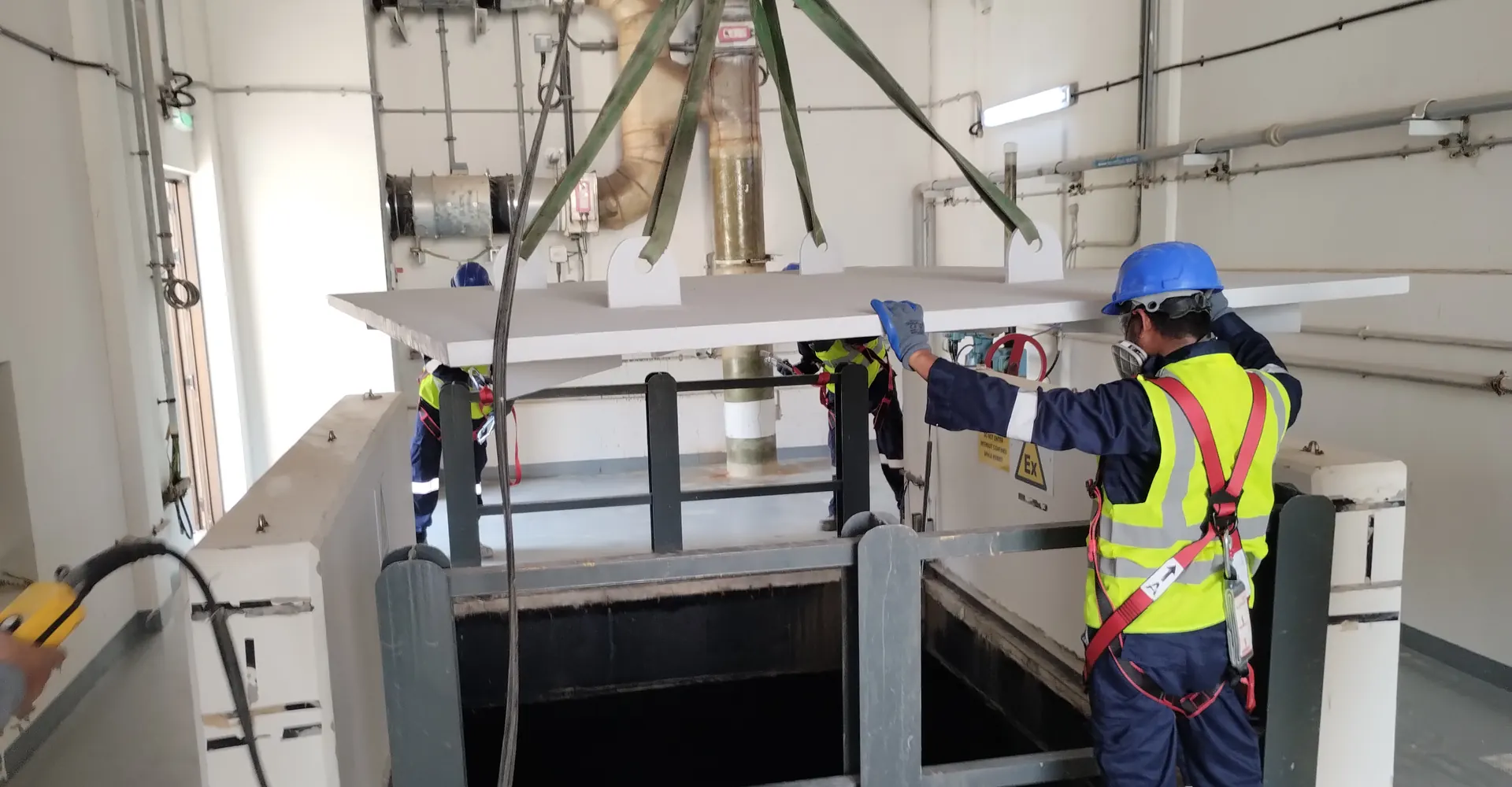 Technicians installing GRP plates over an opening in a plant room